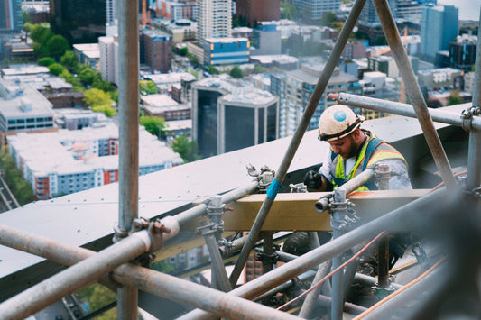 Construction worker on scaffolding overlooking a city skyline, symbolizing digital transformation.